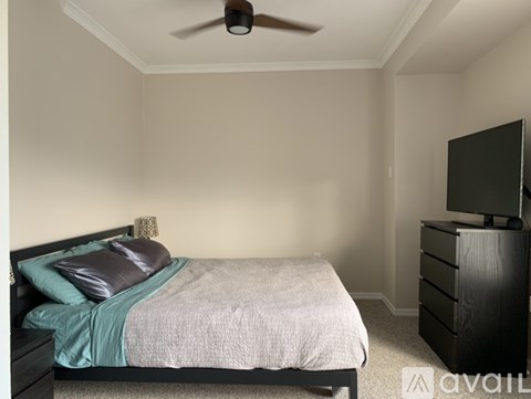 A bedroom with a bed, dresser, and ceiling fan.