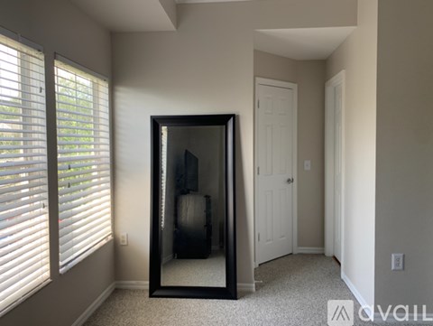 A large mirror in a room with a carpeted floor and a door.