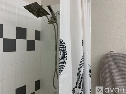 A shower head is mounted on a wall with a black and white checkered tile.