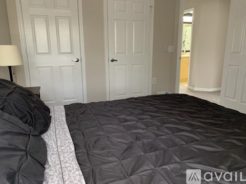 A bedroom with a bed covered in a black comforter.
