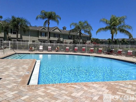 A swimming pool surrounded by palm trees and lounge chairs.