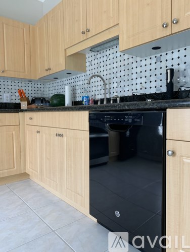 A kitchen with wooden cabinets and a black dishwasher.