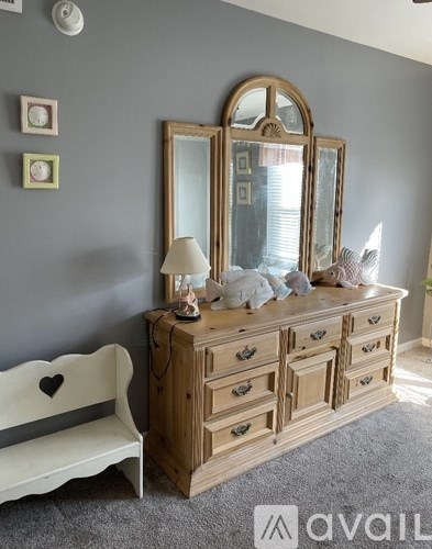 A wooden dresser with a mirror and a bench with a heart design on it.