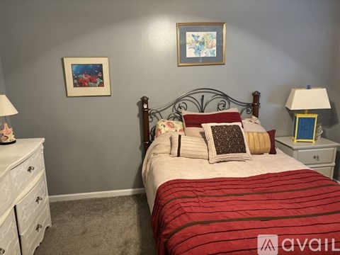 A bedroom with a bed, nightstands, and a painting on the wall.