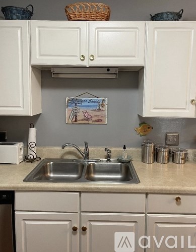A kitchen with a white sink and cabinets.