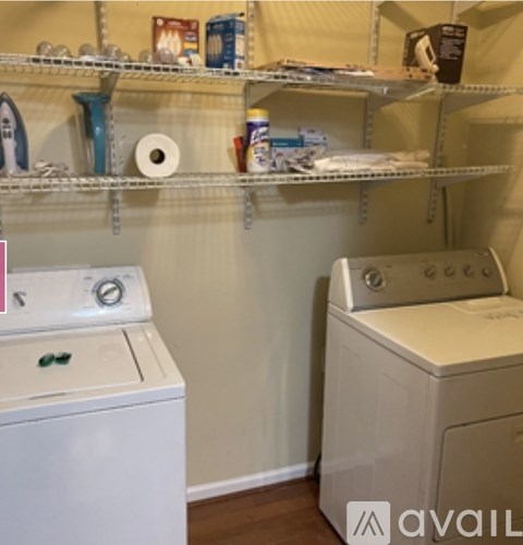 A white washing machine sits next to a white dryer in a small laundry room.