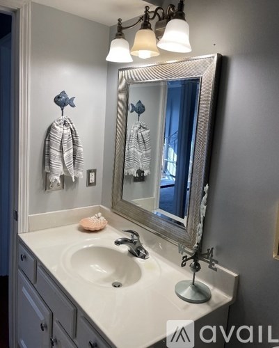 A bathroom with a sink, mirror, and towel rack.