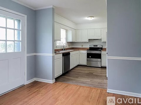 A kitchen with wooden floors and white cabinets.