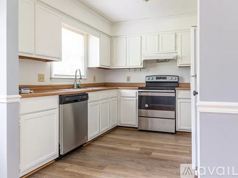 A kitchen with white cabinets and a wooden counter.