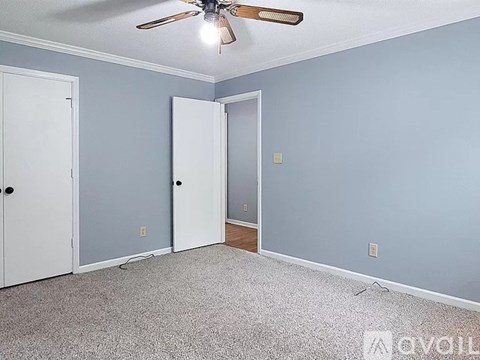 A room with a ceiling fan and two doors.
