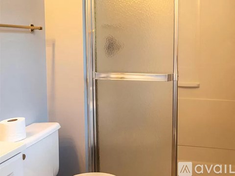 A bathroom with a toilet, a towel rack, and a glass shower door.