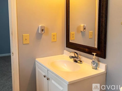 A bathroom with a sink, mirror, and light switches.