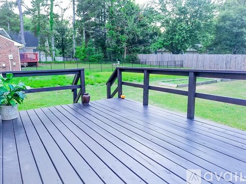 A wooden deck with a railing and a potted plant.