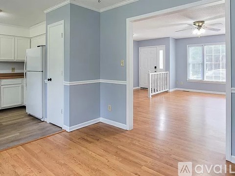A kitchen with a refrigerator, cabinets, and a ceiling fan.