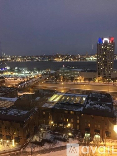A cityscape at night with a tall building with red, white and blue lights on top.