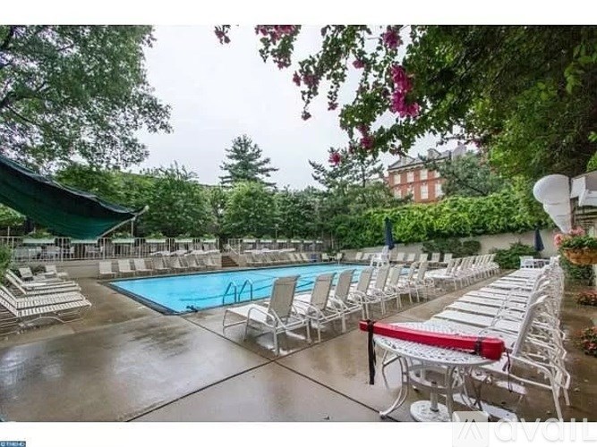 A pool surrounded by white chairs and trees.
