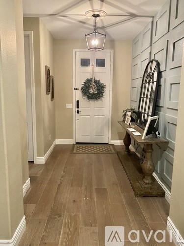 A hallway with a white door and a wreath on it.