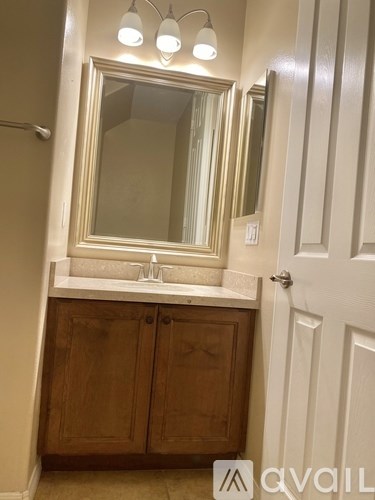 A bathroom with a sink, mirror, and wooden cabinets.