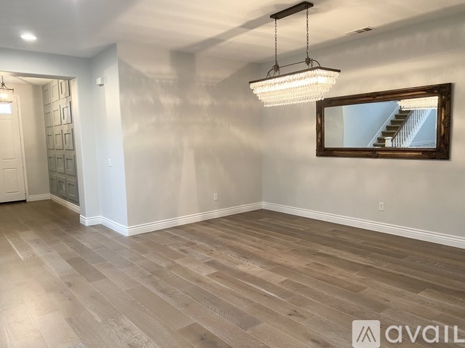 A room with wooden flooring and a mirror on the wall.
