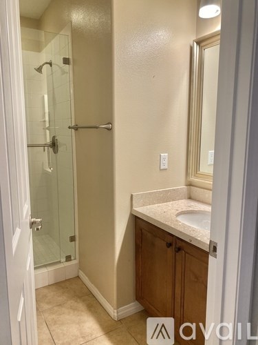 A bathroom with a glass shower door and a white sink.