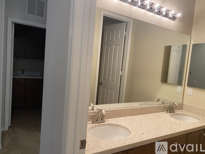 A bathroom with a vanity, sink, mirror, and lighting fixture.