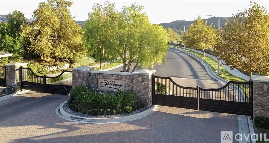A gated entrance to a residential area with a sign that reads "Lantern Village.".