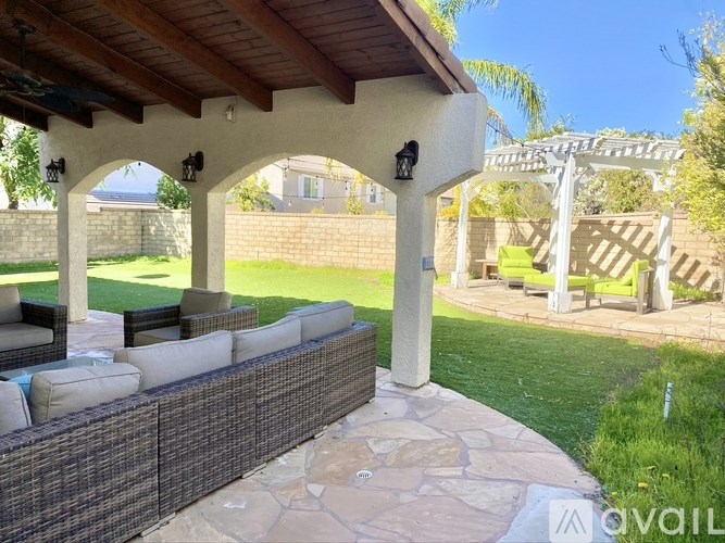 A patio with a stone wall and a wooden pergola.