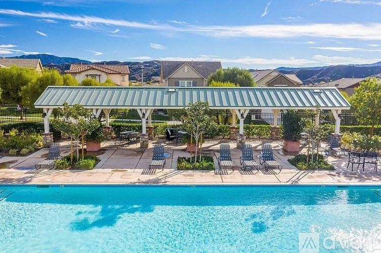 A pool area with a green roof and chairs under a clear blue sky.