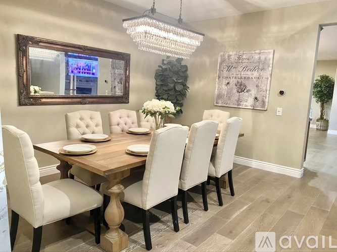 A dining room with a wooden table and white chairs.