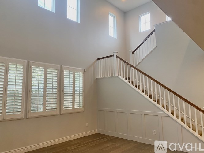 A spacious room with a staircase and windows with shutters.