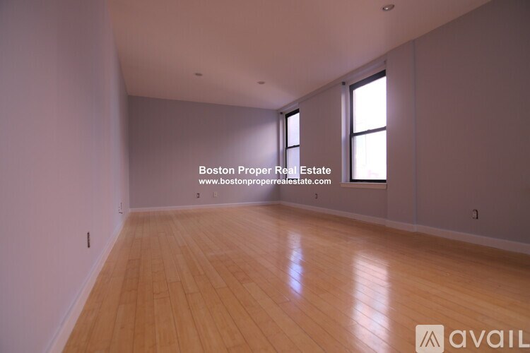A large empty room with wooden floors and two windows.