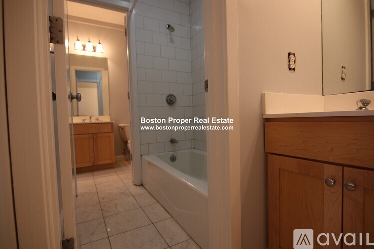 A bathroom with a tub, sink, and mirror.