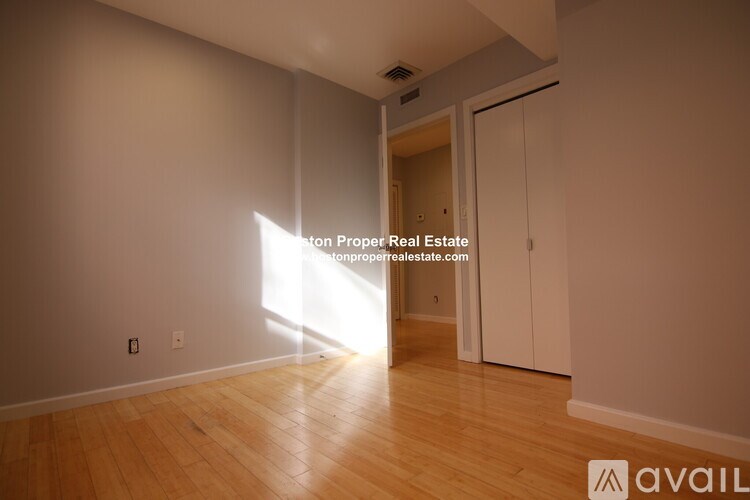 A room with wooden flooring and a doorway leading to another room.
