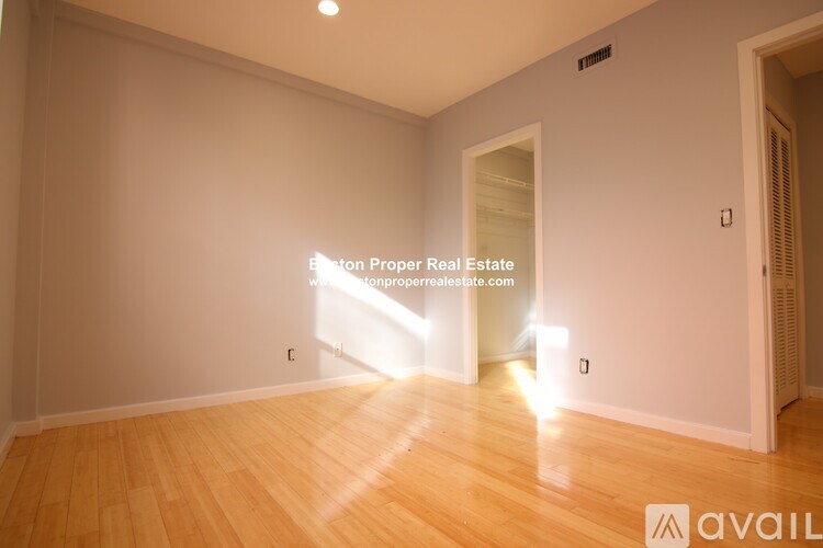 A room with wooden flooring and a doorway leading to another room.