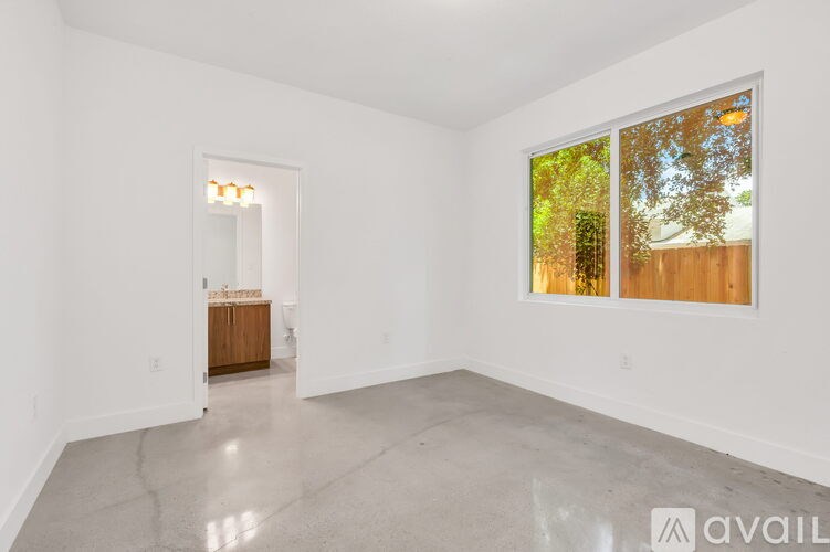 A spacious room with a cabinet and a window showing trees outside.