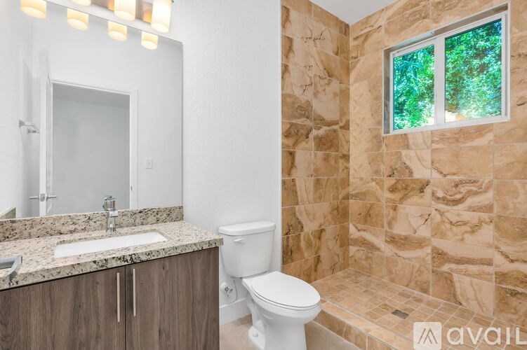 A bathroom with a toilet, sink, and a window.