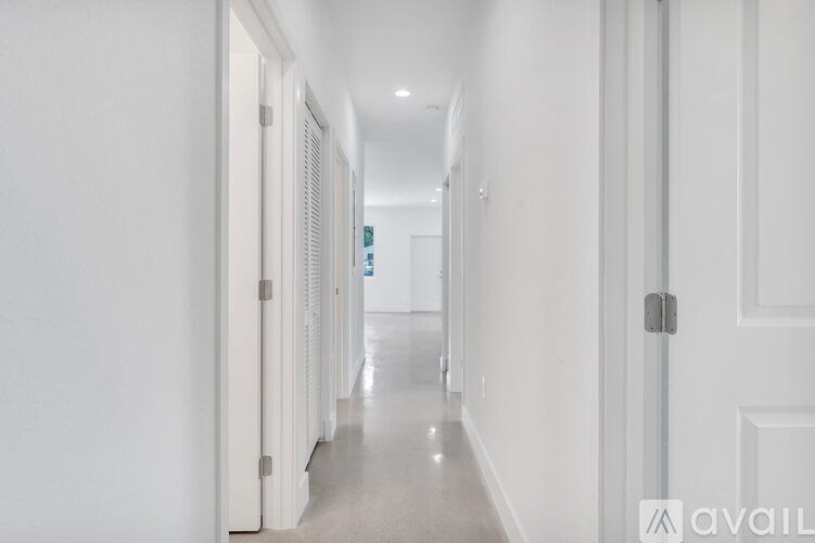 A long white hallway with doors on both sides.