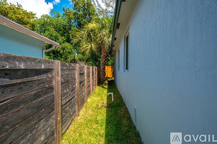 A narrow alley with a wooden fence on the left and a white wall on the right.