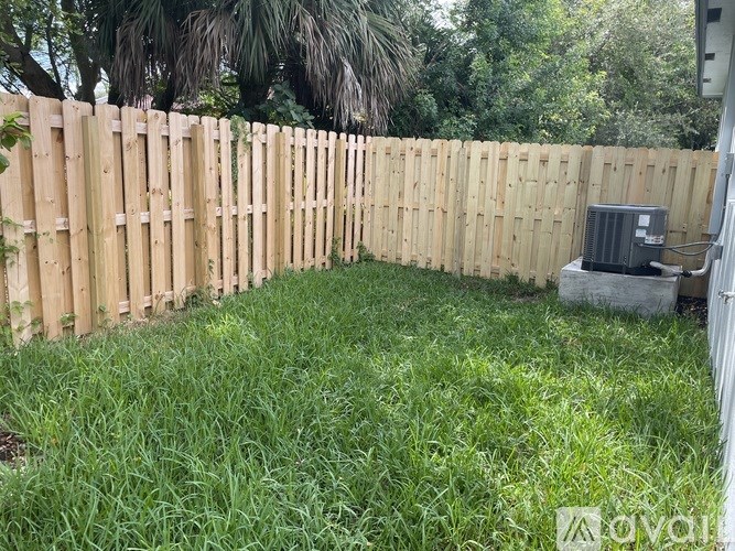 A backyard with a wooden fence and a green lawn.