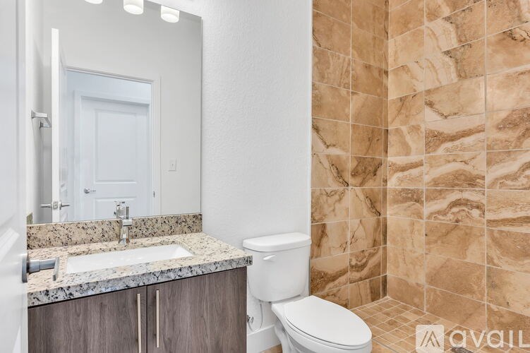 A bathroom with a marble countertop and a tiled shower area.