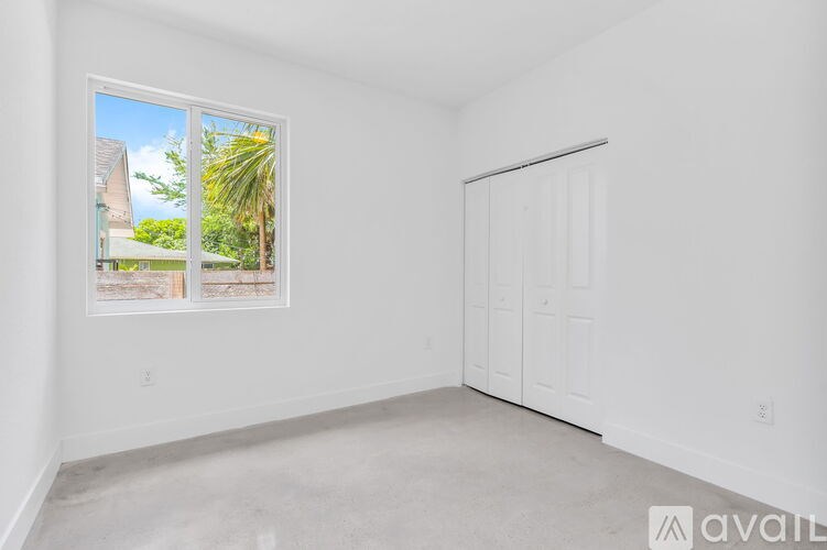 A room with a large window and a white door is available for rent.