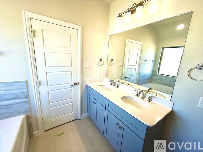 A bathroom with a white door, a white sink, and a mirror.
