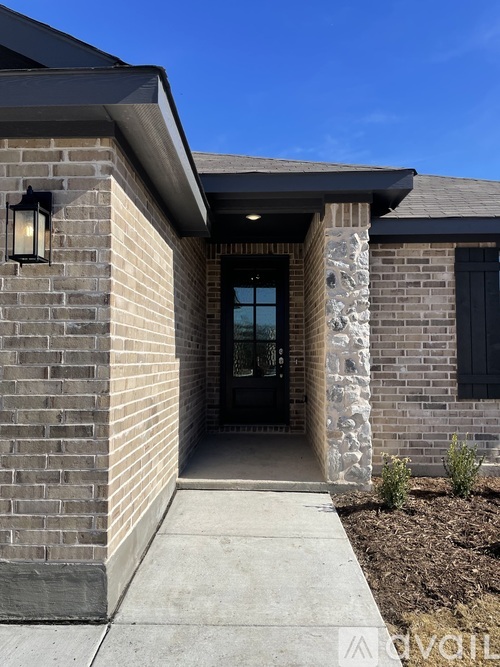 A house entrance with a stone pillar and a black door.