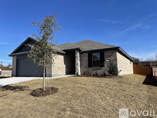 A house with a grey roof and a tree in front of it.