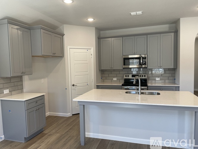 A kitchen with a white countertop and grey cabinets.