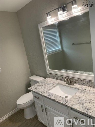 A bathroom with a toilet, sink, and mirror.