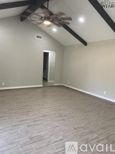 A room with a ceiling fan and wooden flooring.