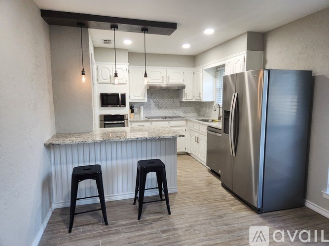 A kitchen with a refrigerator, microwave, and oven.