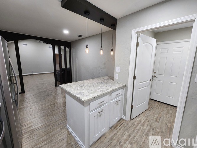 A kitchen with a white island and wooden floors.