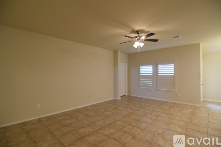 A room with a ceiling fan and a window with blinds.